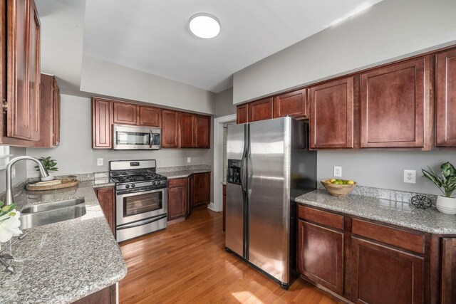 1542 S 4th St, Columbus, OH 43207 - kitchen featuring light stone counters, light wood-style floors, appliances with stainless steel finishes, and a sink
