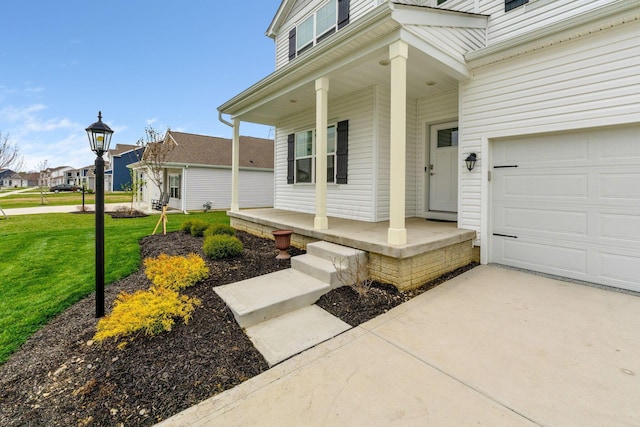 view of exterior entry featuring driveway, a porch, a garage, and a yard