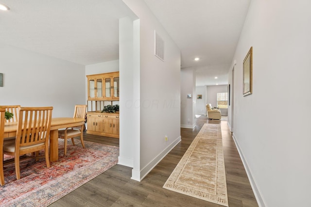 corridor featuring recessed lighting, dark wood-type flooring, baseboards, and visible vents