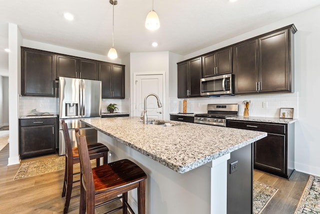 kitchen featuring a breakfast bar area, light wood-style floors, a sink, and stainless steel appliances