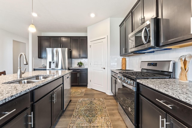 kitchen featuring dark wood-style flooring, backsplash, a sink, light stone countertops, and appliances with stainless steel finishes