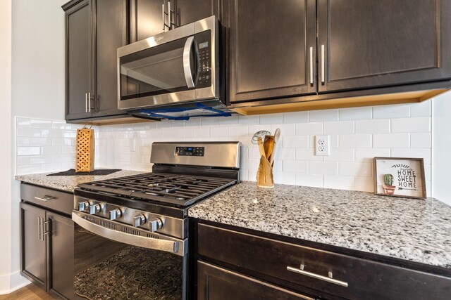 kitchen with dark brown cabinets, light stone counters, tasteful backsplash, and stainless steel appliances