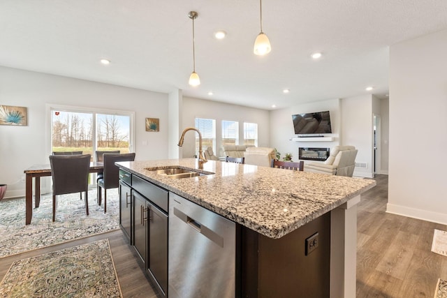kitchen with hanging light fixtures, dark wood-style floors, a sink, and stainless steel dishwasher