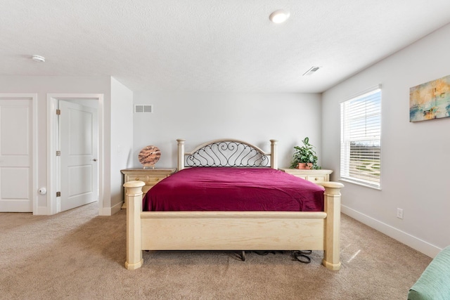 bedroom featuring light colored carpet, visible vents, baseboards, and a textured ceiling