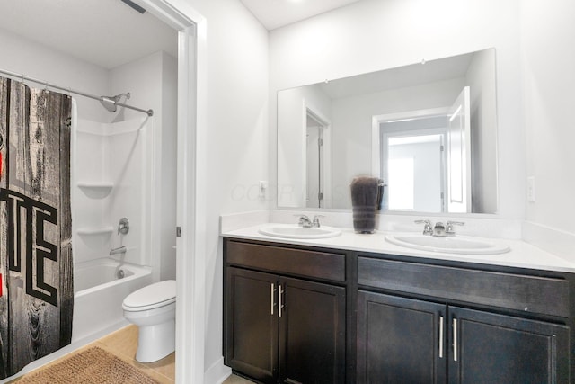bathroom with double vanity, a sink, toilet, and tile patterned flooring