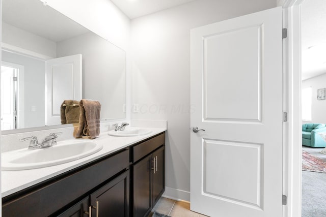 bathroom featuring double vanity, a sink, baseboards, and tile patterned flooring