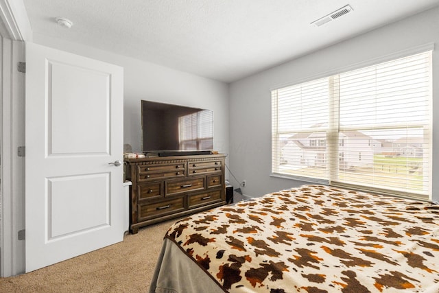 bedroom featuring a textured ceiling, visible vents, and light carpet