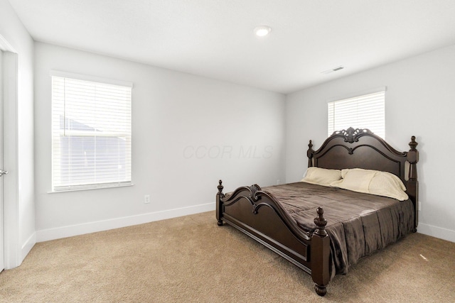 bedroom featuring baseboards, light colored carpet, and visible vents