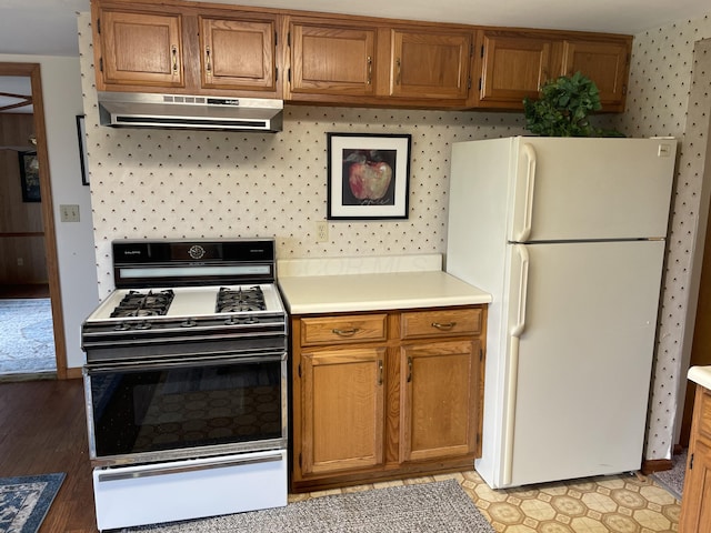 14963 Payne Rd, Marysville, OH 43040 - kitchen featuring light countertops, wallpapered walls, gas stove, under cabinet range hood, and freestanding refrigerator
