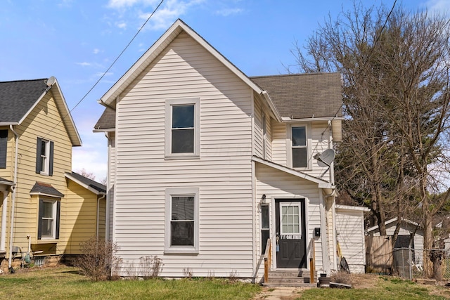 traditional home with a shingled roof, entry steps, and fence