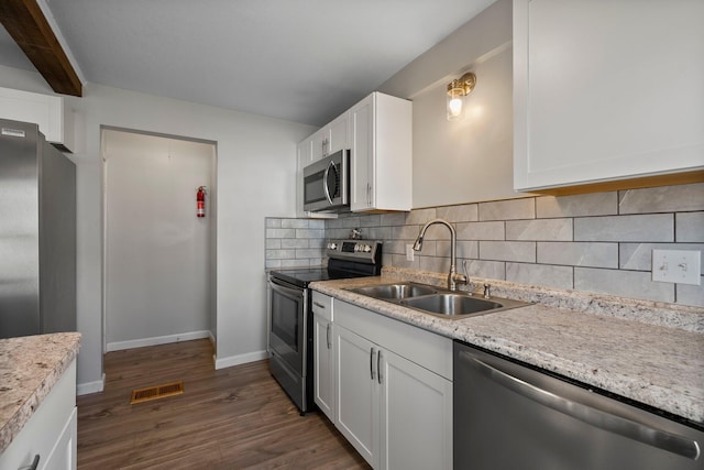 kitchen with a sink, tasteful backsplash, appliances with stainless steel finishes, visible vents, and dark wood-type flooring