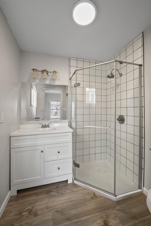 full bathroom featuring vanity, a shower stall, and wood finished floors
