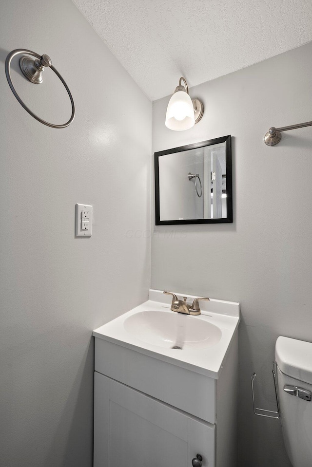 bathroom with toilet, vanity, and a textured ceiling