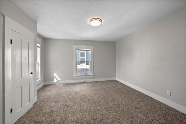 empty room with baseboards, carpet floors, and a textured ceiling