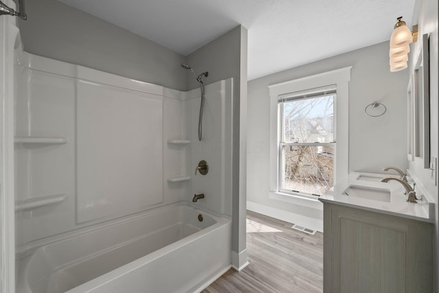 full bathroom featuring bathtub / shower combination, a sink, wood finished floors, baseboards, and visible vents
