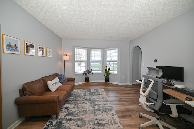 home office with baseboards, arched walkways, wood finished floors, and a textured ceiling