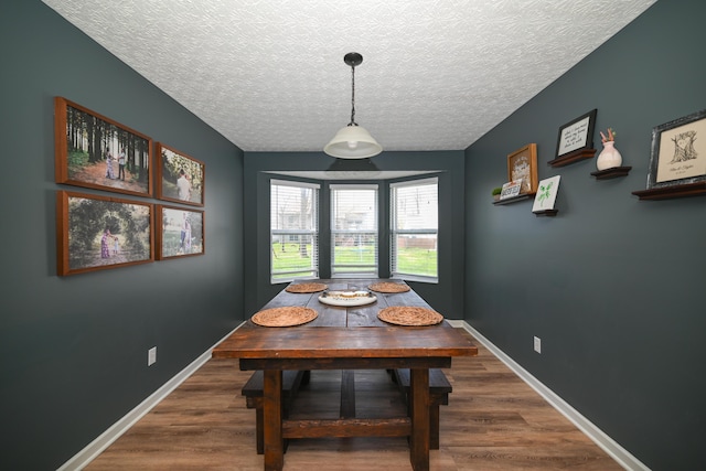 dining space featuring baseboards, a textured ceiling, and wood finished floors