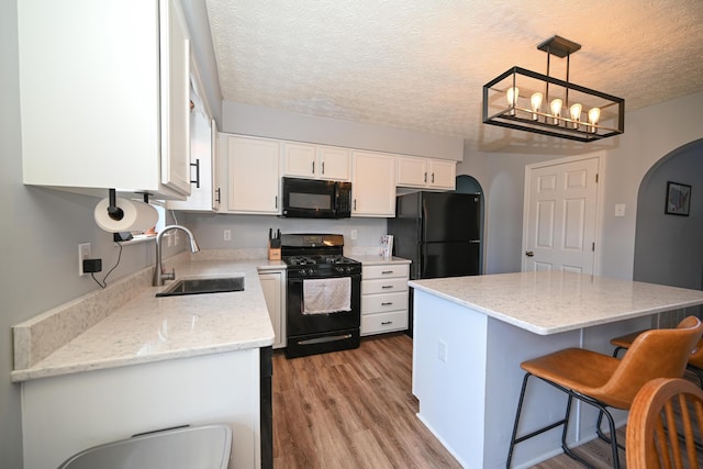 kitchen with a sink, white cabinets, black appliances, and arched walkways