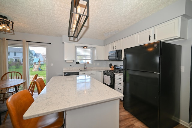 kitchen featuring a sink, white cabinets, black appliances, and a center island