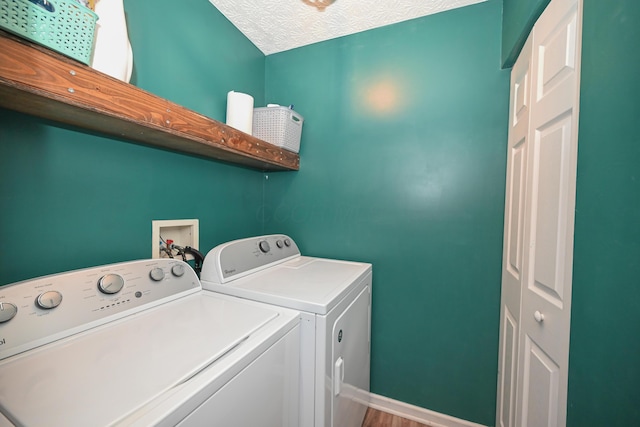 clothes washing area with baseboards, laundry area, washing machine and clothes dryer, and a textured ceiling