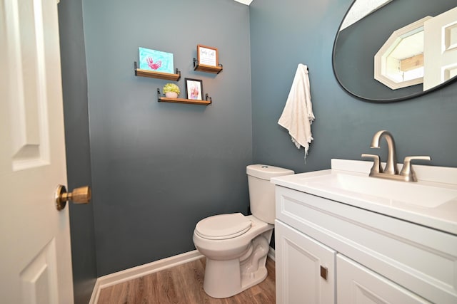 bathroom featuring toilet, vanity, wood finished floors, and baseboards