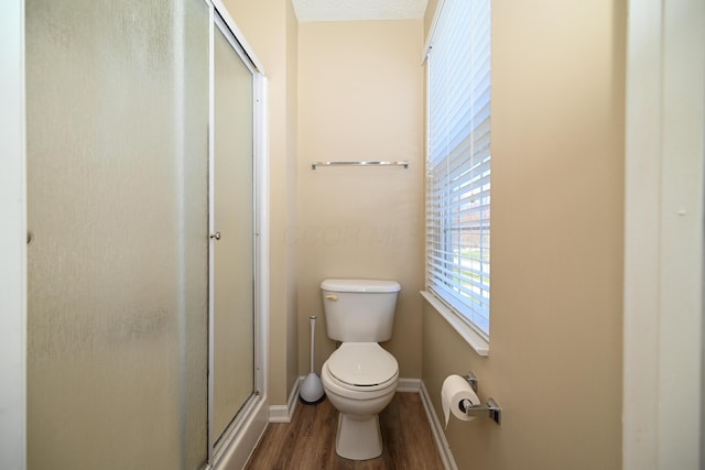 full bath with toilet, baseboards, a stall shower, and wood finished floors