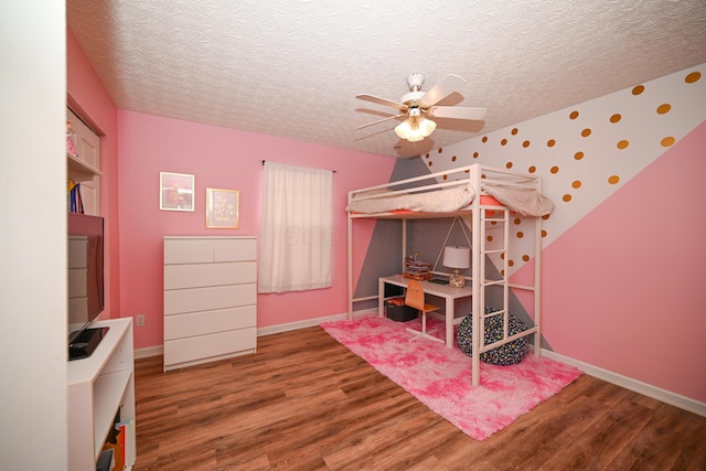bedroom with a textured ceiling, baseboards, a ceiling fan, and wood finished floors