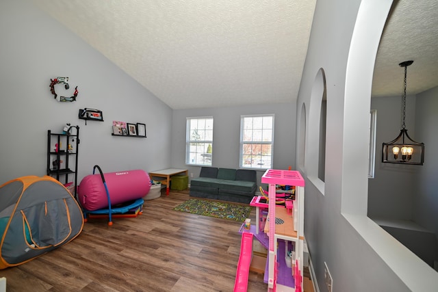 playroom with a chandelier, lofted ceiling, a textured ceiling, and wood finished floors