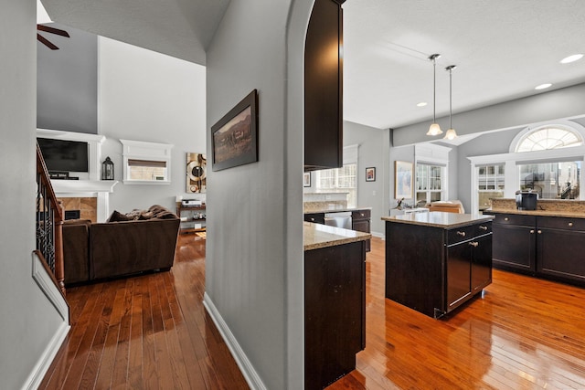 4600 Hirth Hill Rd E, Grove City, OH 43123 - kitchen featuring light stone counters, hardwood / wood-style flooring, a fireplace, open floor plan, and arched walkways
