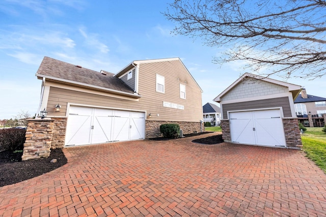 4600 Hirth Hill Rd E, Grove City, OH 43123 - view of home's exterior with stone siding, an outbuilding, a garage, and decorative driveway
