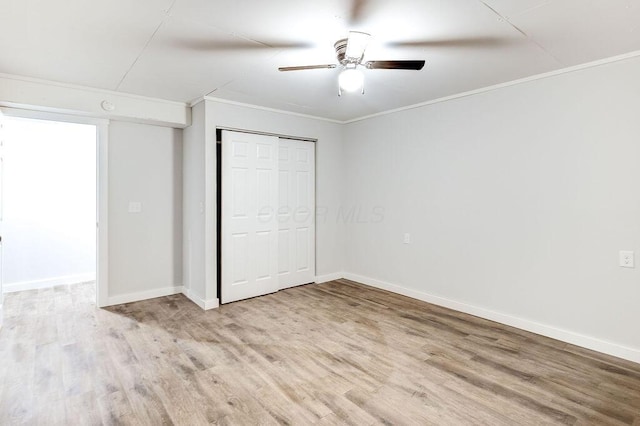 unfurnished bedroom with a closet, ornamental molding, baseboards, and light wood-type flooring