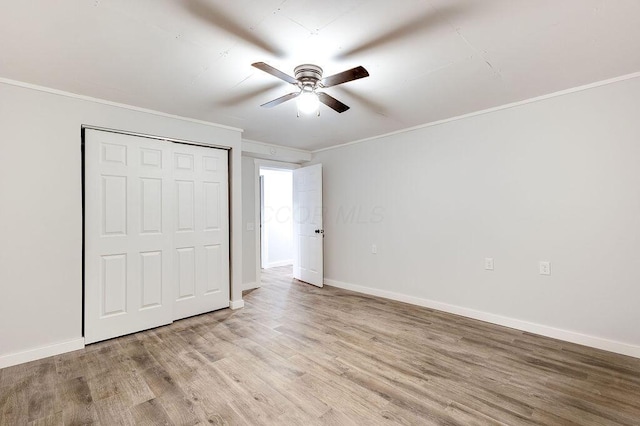 unfurnished bedroom with a closet, crown molding, a ceiling fan, baseboards, and light wood-style floors