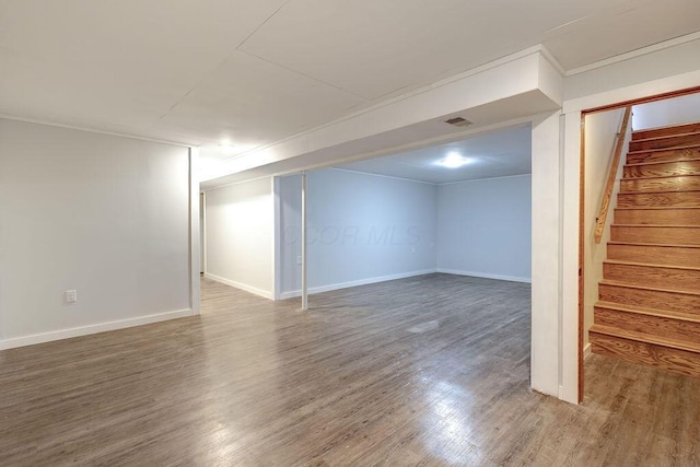 finished below grade area featuring baseboards, stairs, visible vents, and wood finished floors