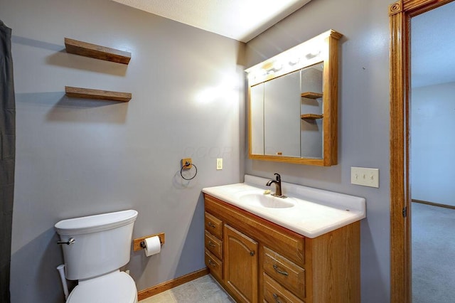 bathroom with toilet, vanity, and baseboards