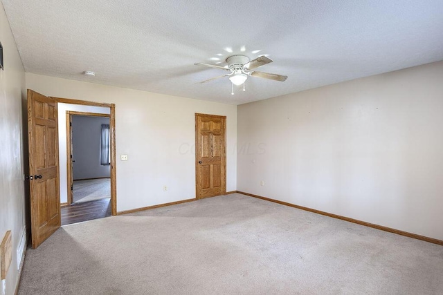 carpeted spare room with baseboards, a textured ceiling, and ceiling fan