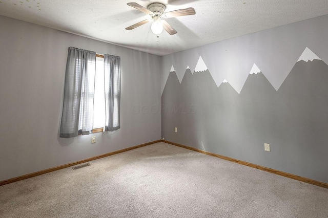 carpeted spare room with a textured ceiling, baseboards, ceiling fan, and visible vents