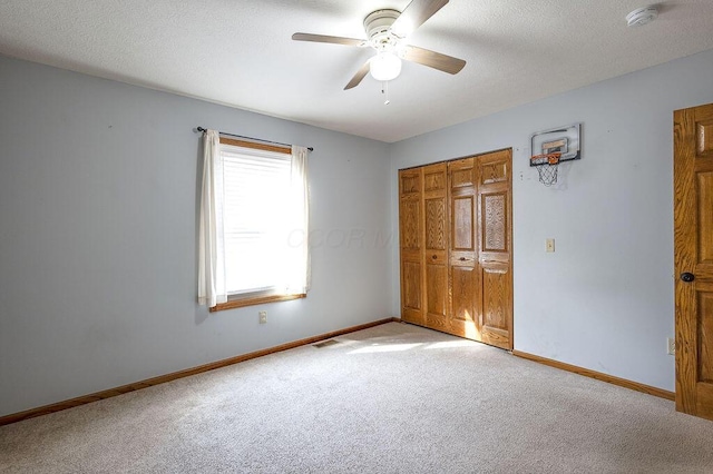unfurnished bedroom featuring a closet, light carpet, a textured ceiling, baseboards, and visible vents