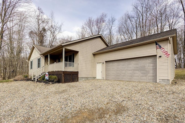 ranch-style house featuring covered porch, gravel driveway, a garage, and a shingled roof