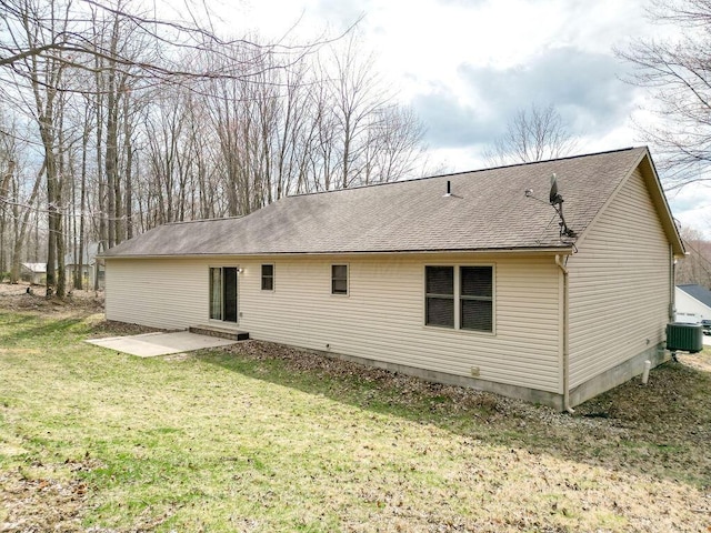 rear view of property featuring a shingled roof, entry steps, central AC, and a yard