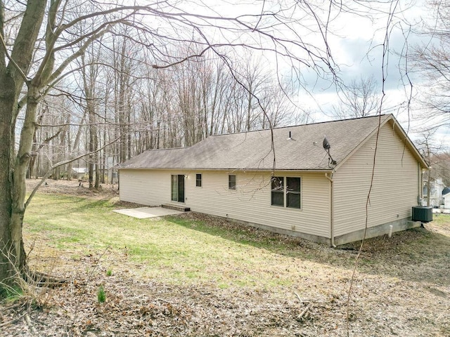 rear view of house featuring a patio, a shingled roof, cooling unit, and a yard