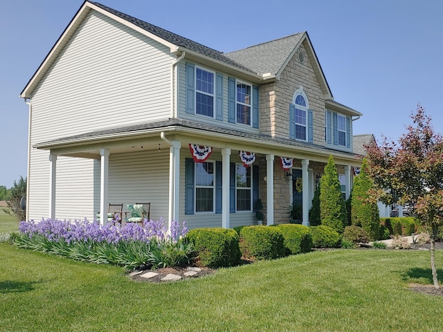 view of front of house featuring covered porch, a front yard, and roof with shingles