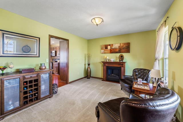 living area with a fireplace, baseboards, and carpet