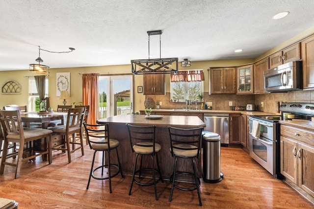 kitchen featuring light wood-type flooring, stainless steel appliances, a sink, and a kitchen island