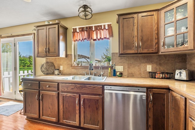 kitchen featuring light countertops, tasteful backsplash, dishwasher, and a sink