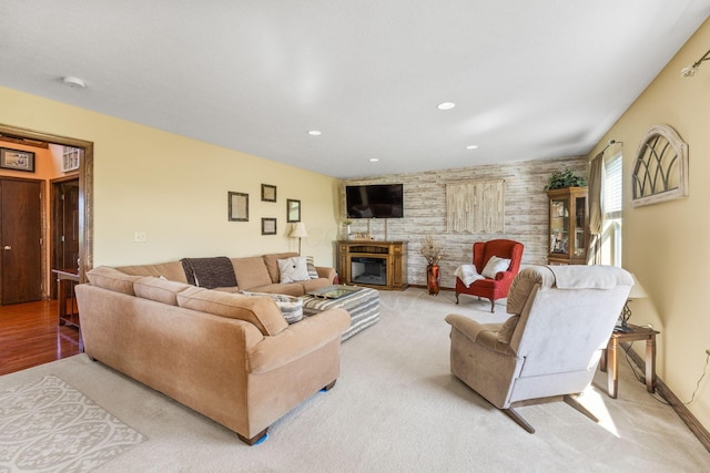 living room with recessed lighting, a glass covered fireplace, and light colored carpet