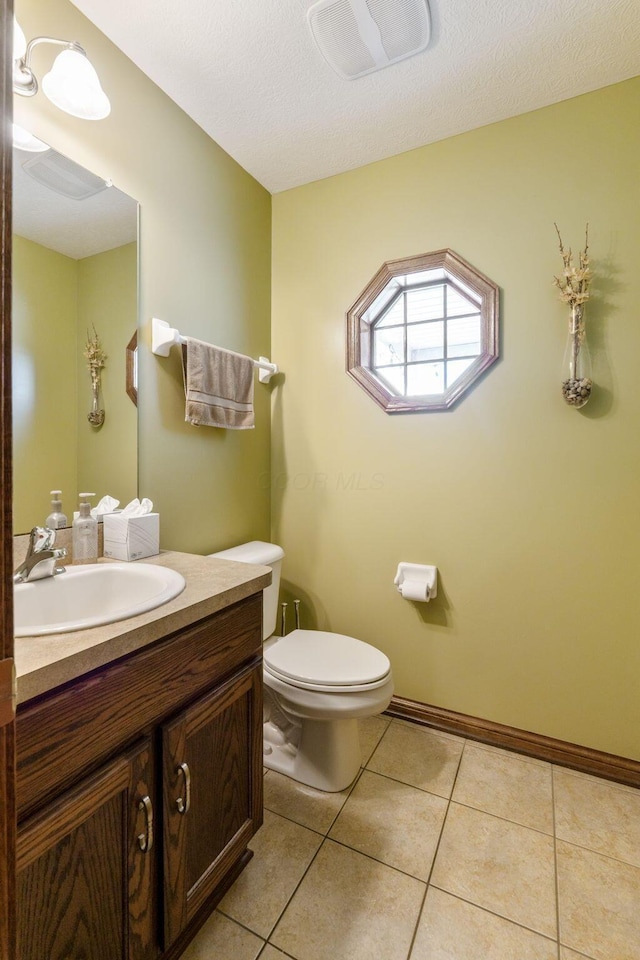 bathroom featuring baseboards, vanity, tile patterned flooring, and toilet