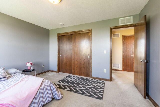 carpeted bedroom with a closet, visible vents, and baseboards