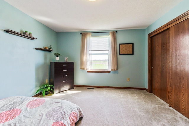 carpeted bedroom with baseboards, visible vents, and a closet
