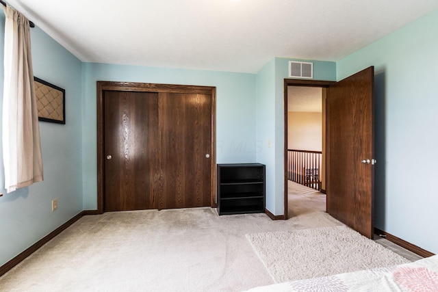 unfurnished bedroom featuring visible vents, light carpet, baseboards, and a closet