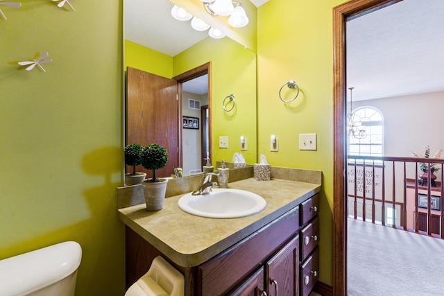 bathroom featuring toilet, vanity, and visible vents